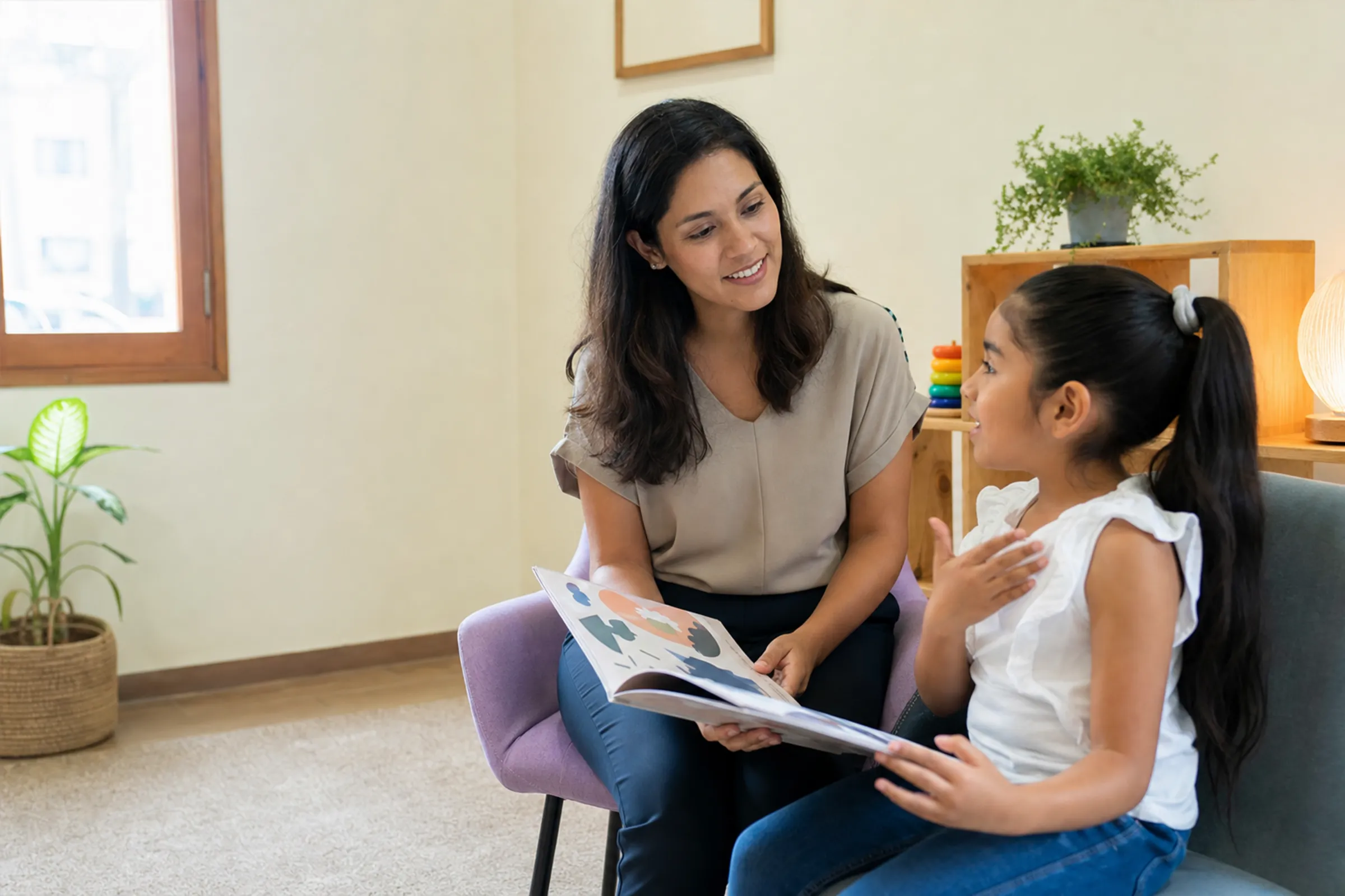 Terapeuta escucha a una niña durante una actividad de comunicación con un libro.